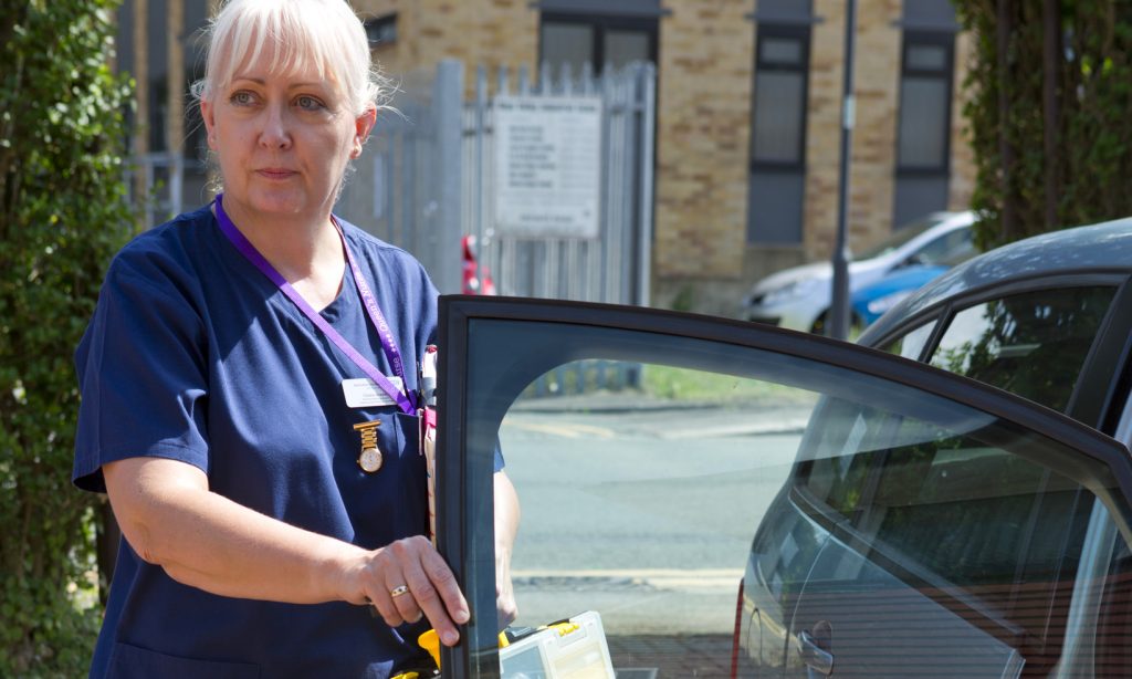A district nurse opens the door of her car