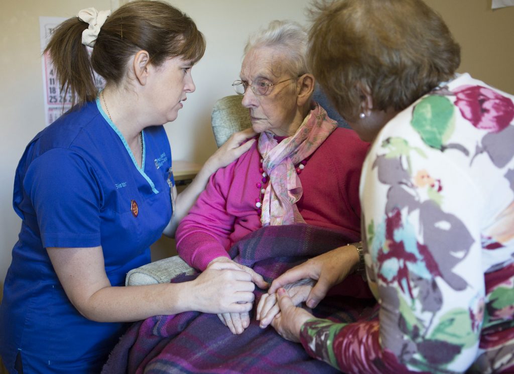 Nurse visiting elderly woman with her carer in the foreground