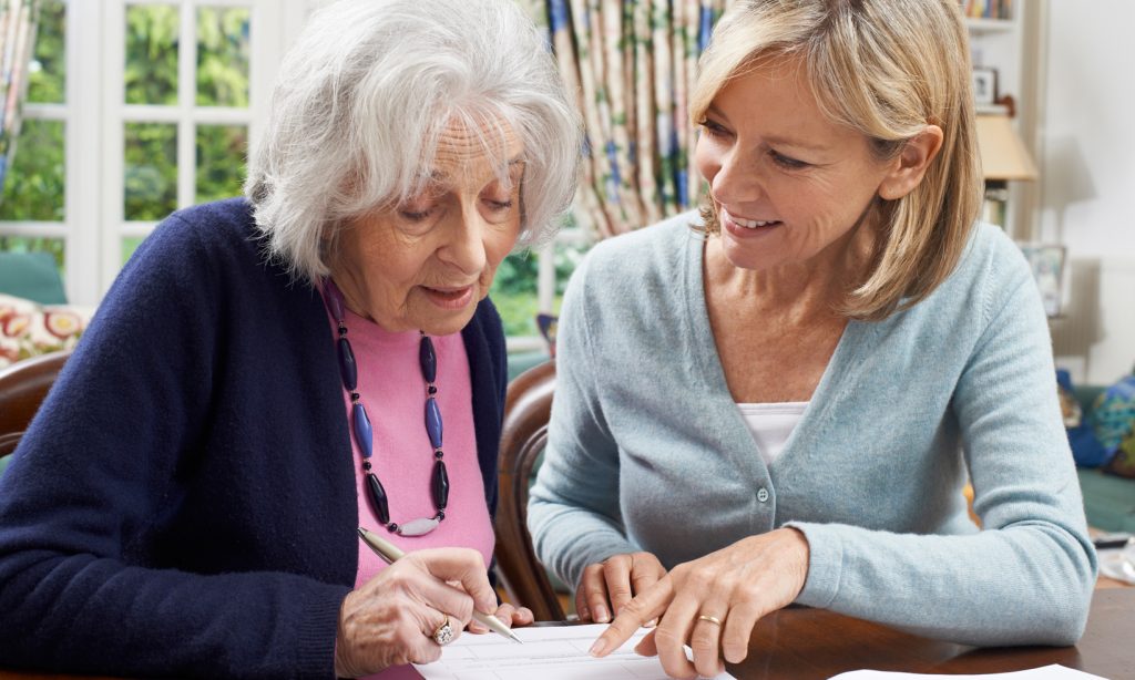 Younger woman helps an retired nurse fill in a form