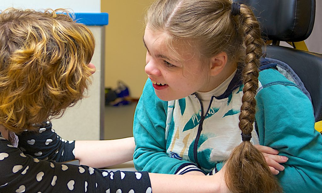 Nurse interacts with a young girl with plaits with a learning disability