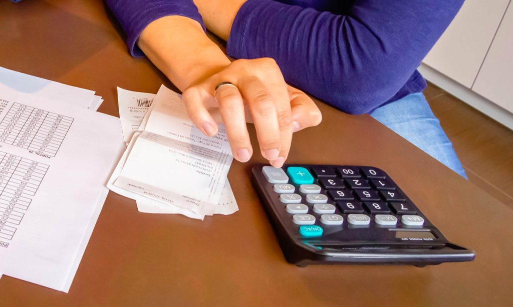 A woman uses a calculator to access the level of her domestic debt