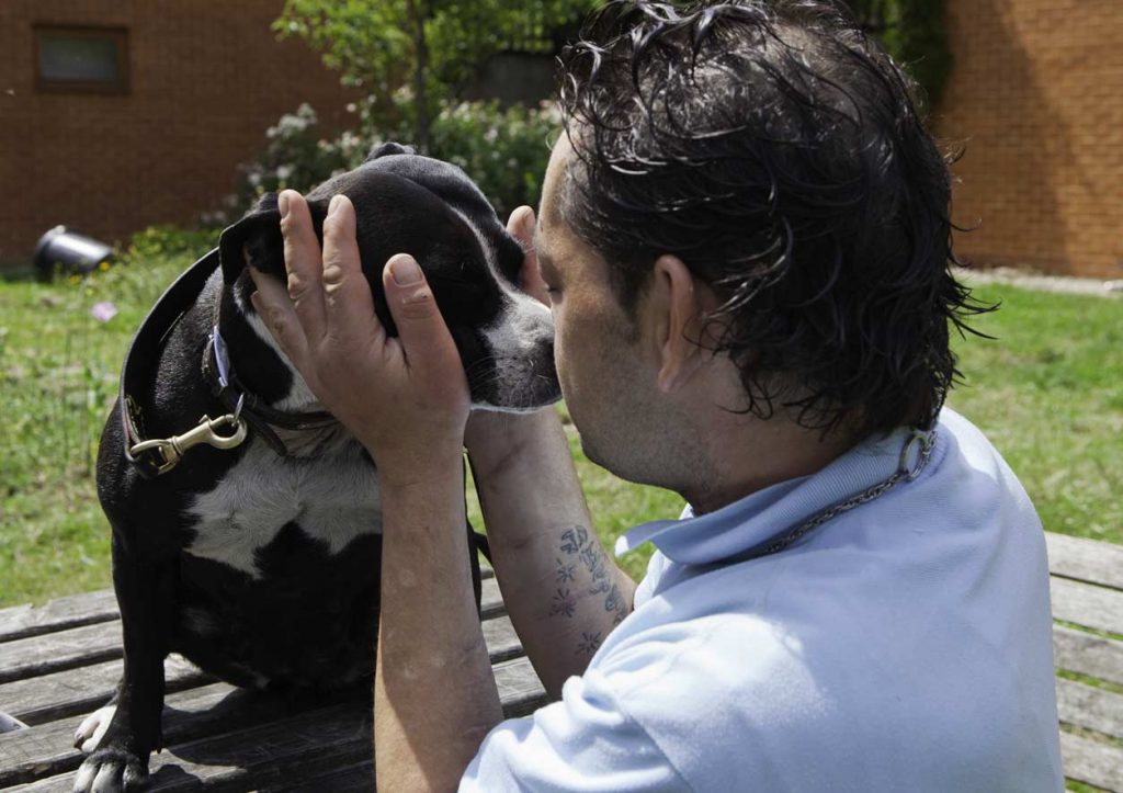 A homeless man kisses his pet dog
