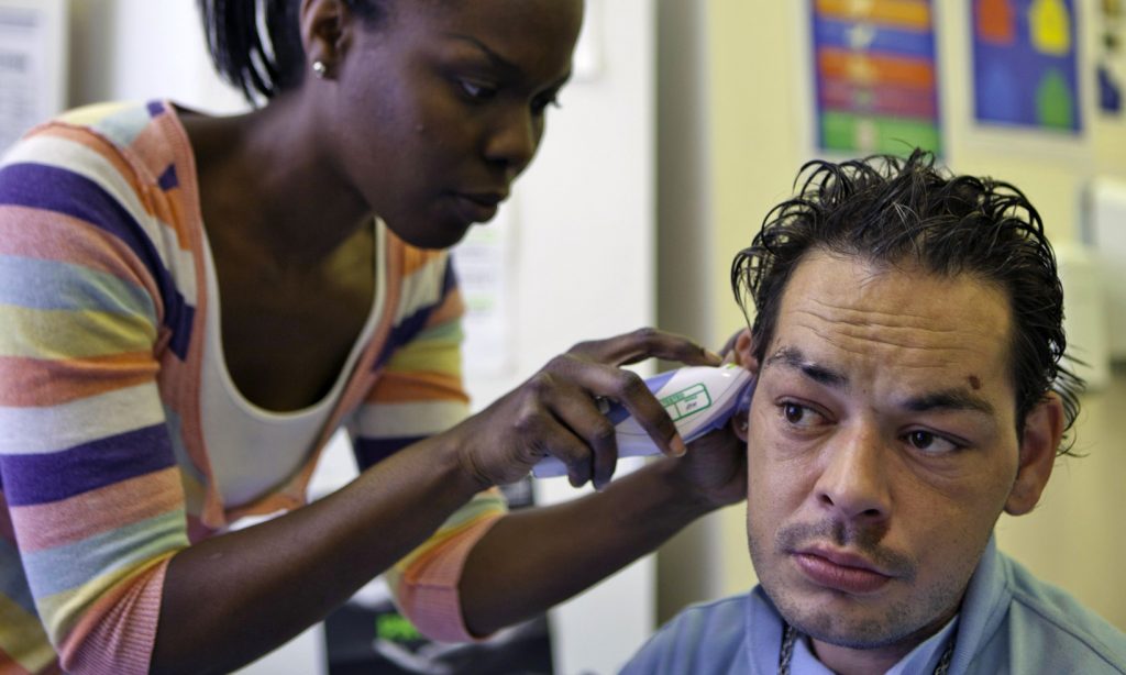 A homeless man has his temperature checked using an ear themometer