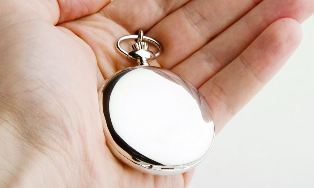 A silver pocket watch in the hand