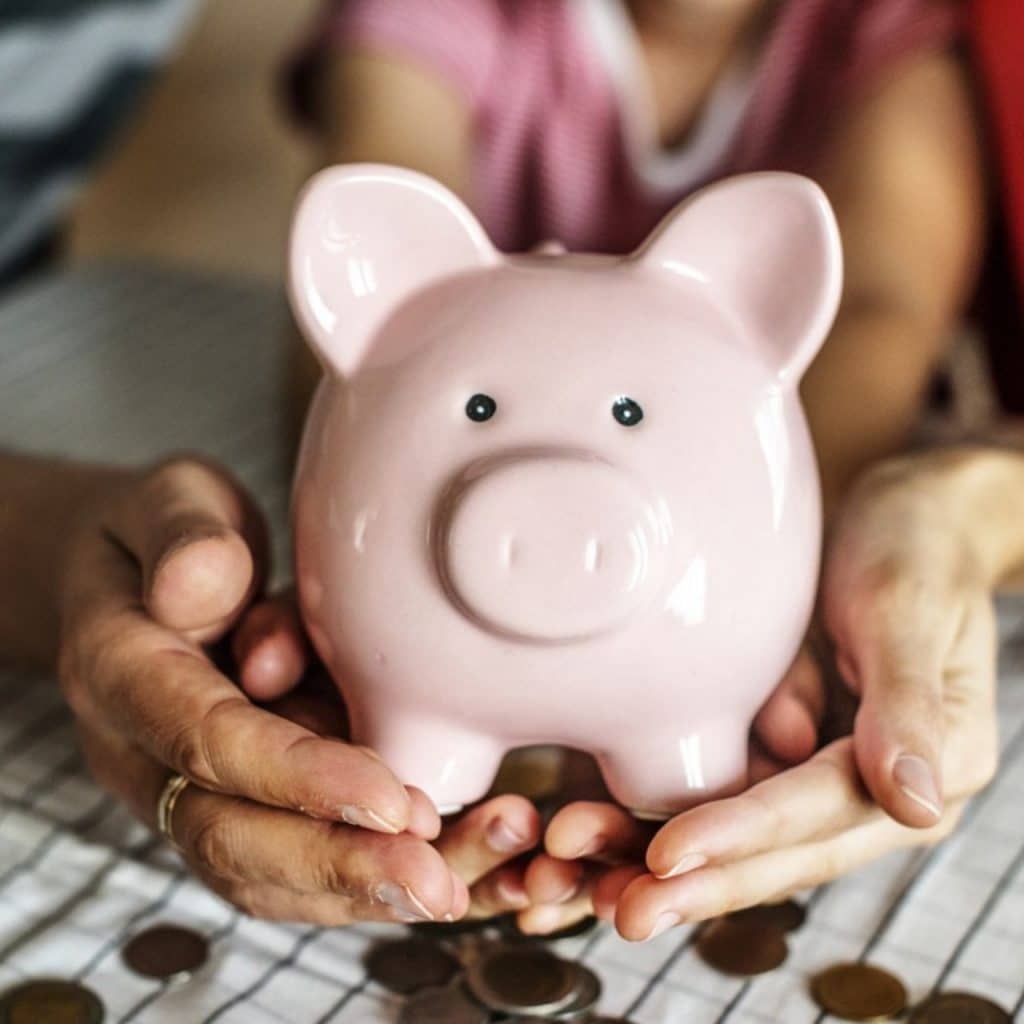 An image of a person holding pink ceramic pig coin bank