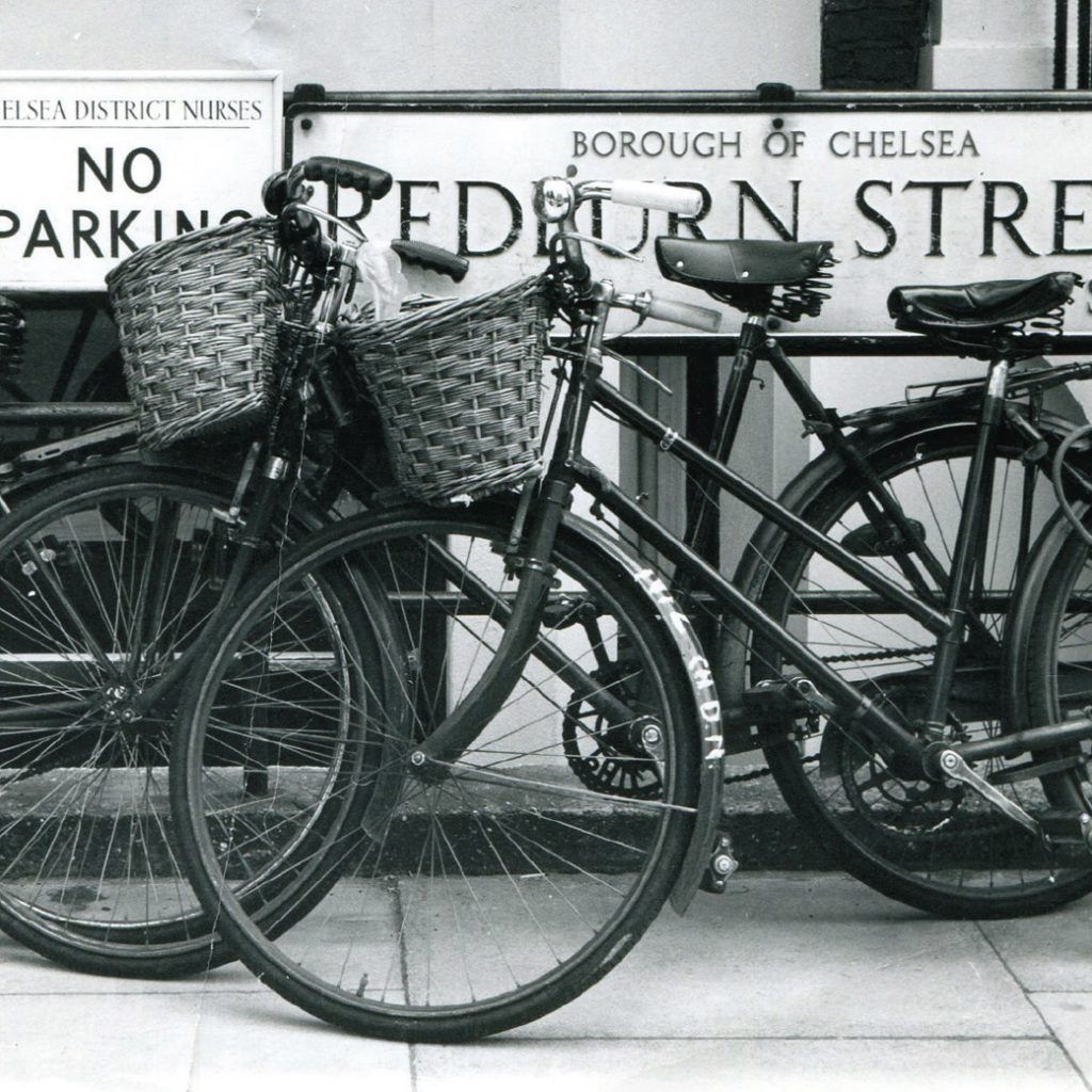 Nurses pushbikes with baskets against railings in Chelsea, 1950s