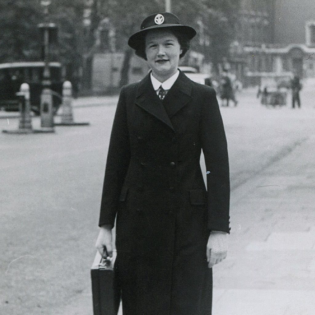 A district nurse from early 20C walking in a city street