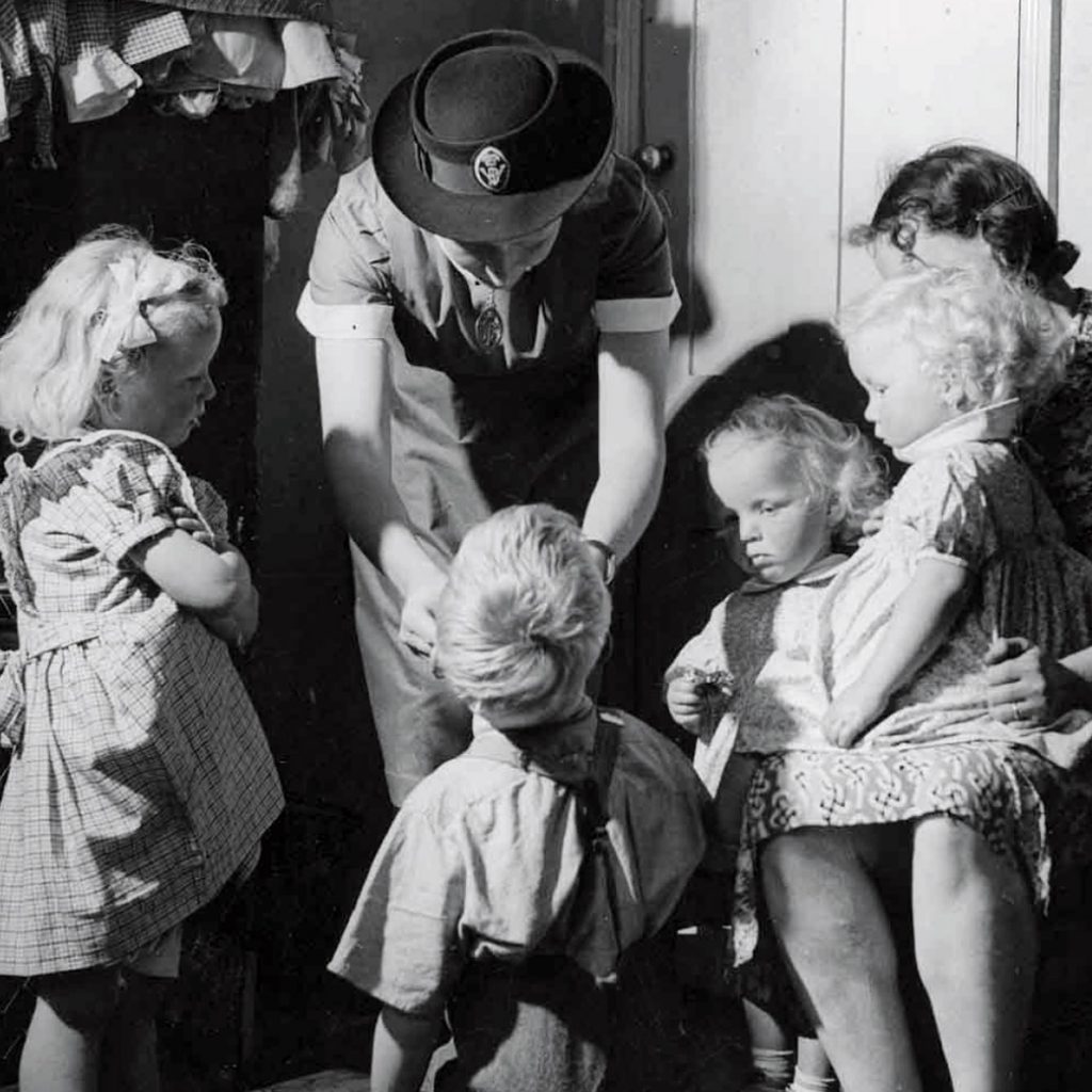A nurse inspecting children for tonsillitis in early 20C