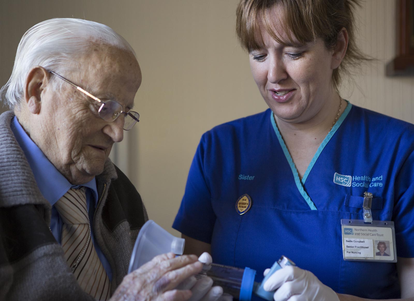 A district nurse helping an elderly man with an inhaler
