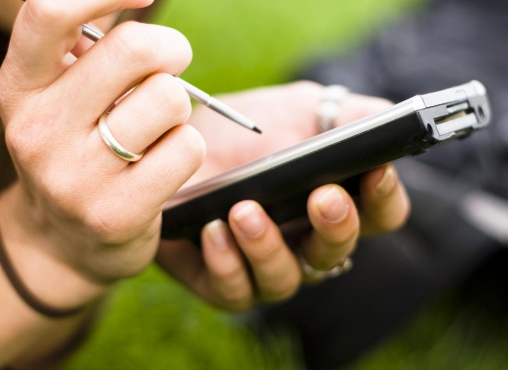 A woman using a smartphone with a pen