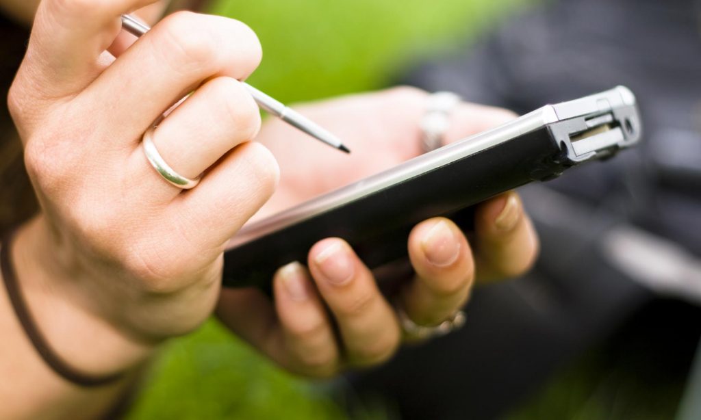 A woman using a smartphone with a pen