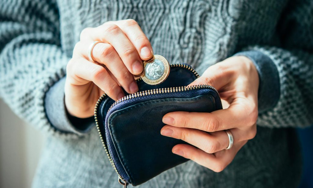 A woman taking a pound coin out of a small leather purse