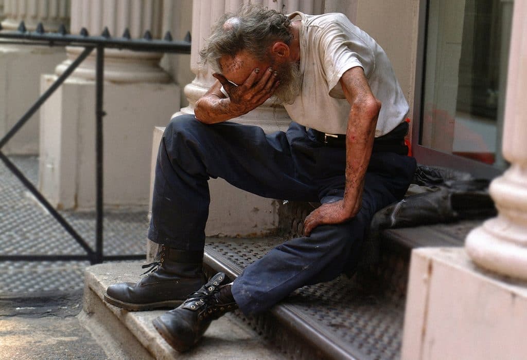 An image of a homeless man looking ill.
