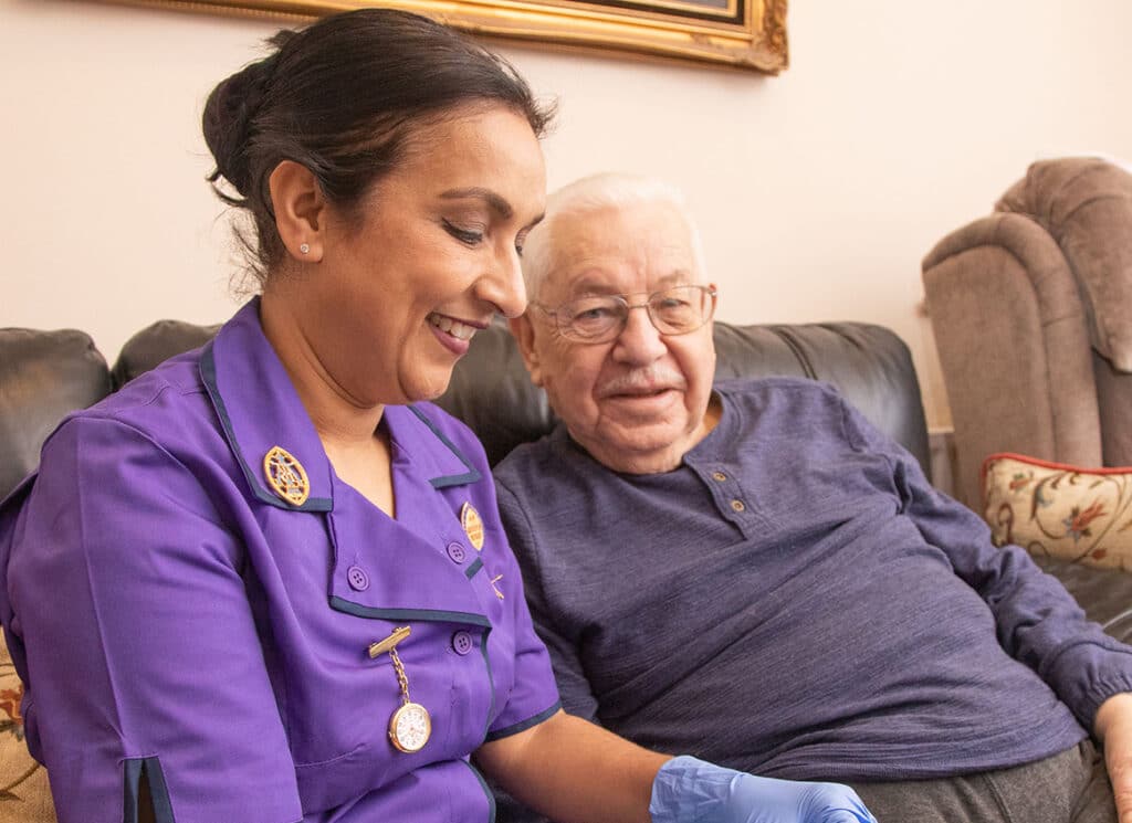 A district nurse talks to an elderly man in his home