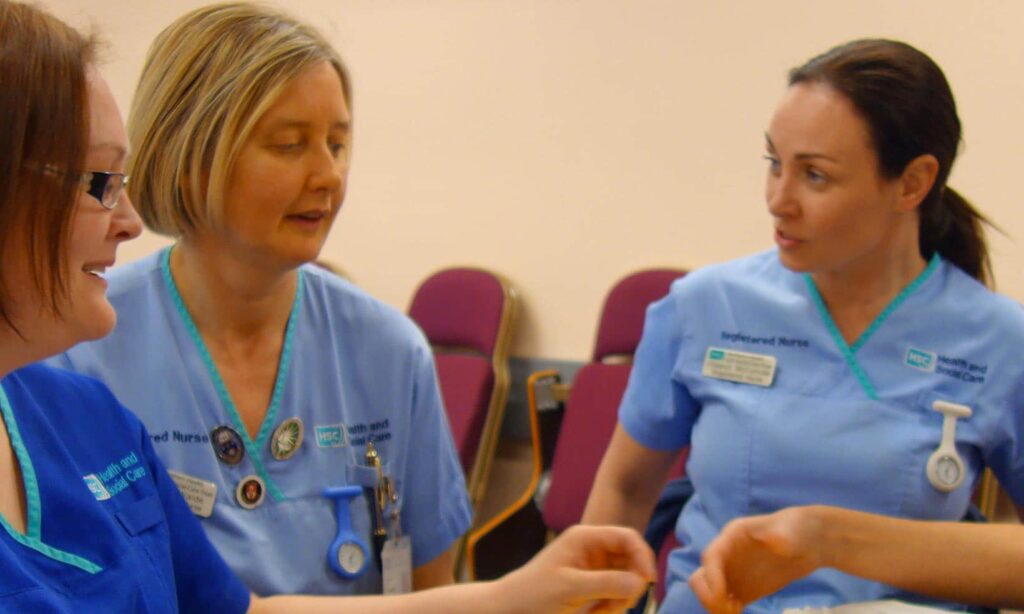 A group of nurses in blue uniforms in a study meeting